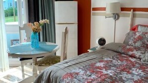 Een hotelkamer met een bed, een tafel met bloemen, een stoel, een raam met gordijnen en uitzicht.