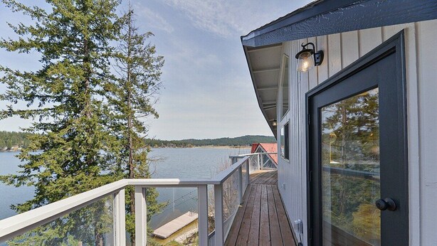 Eine Holzterrasse mit einer Glastür und Blick auf einen See.