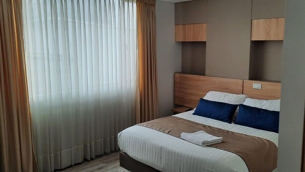A hotel room with a bed, curtains, and a headboard. - HOTEL EXPO INN AGORA  (Bogotá)