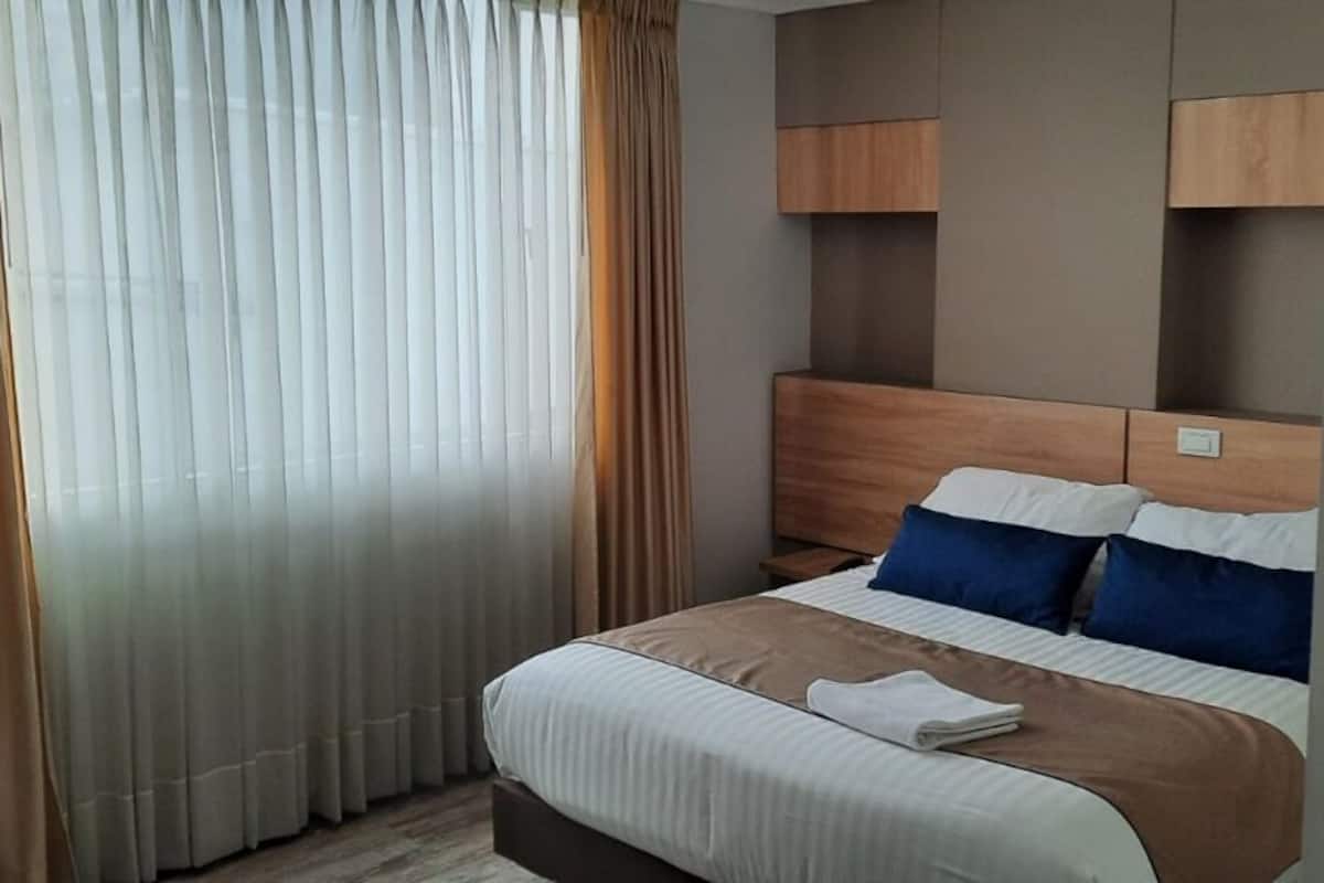 Une chambre d’hôtel avec un lit, des rideaux et une tête de lit.