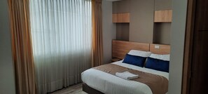 Une chambre d’hôtel avec un lit, des rideaux et une tête de lit.