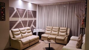A modern living room with two beige sofas, a small round table, and a decorative wall panel. - HOTEL EXPO INN AGORA  (Bogotá)