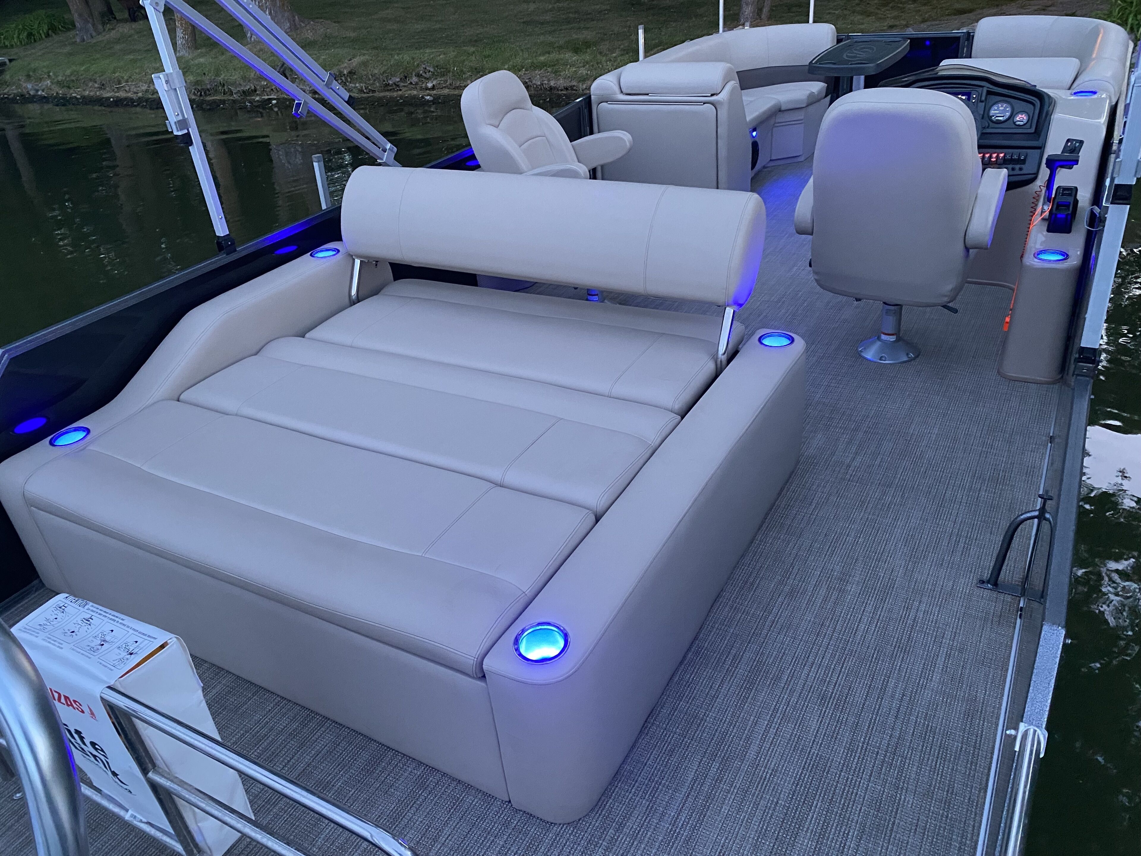 L'intérieur d'un bateau, avec un espace salon doté de sièges rembourrés, un panneau de commande et une vue sur l'eau.