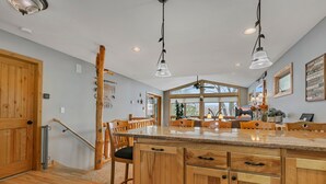 Een ruime keuken met houten kastjes, een groot eiland en hanglampen.