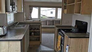 Een kleine keuken met houten kastjes, een inbouwoven en een spoelbak.