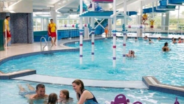 Een zwembadgedeelte met meerdere banen, een duikplank en een waterglijbaan.