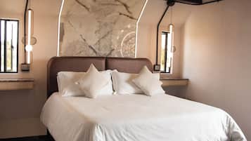 Un dormitorio moderno con una cama grande, dos mesitas de noche, una pared de mármol e iluminación colgante.
