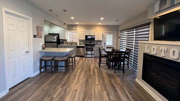 A modern kitchen with a central island, stainless steel appliances, and a dining area with a fireplace.