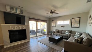 A spacious living room with a large LOTO fireplace, a ceiling fan, and a sliding glass door leading to a patio.