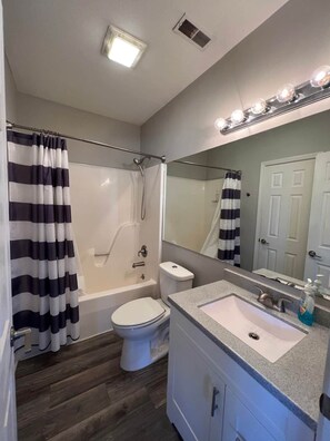 A bathroom with a shower, toilet, and sink.