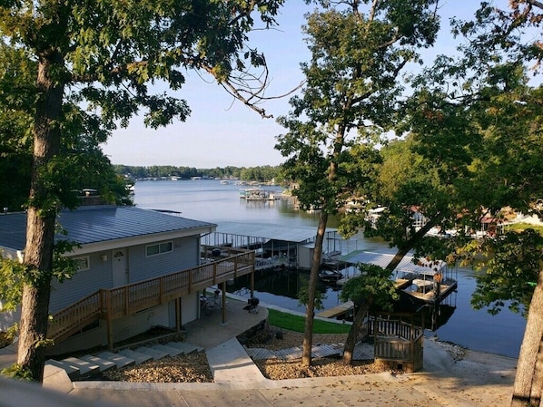 A lakeside property with a dock, a covered outdoor seating area, and a building with a deck.