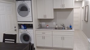 A laundry room with a washing machine, a sink, and cabinets.