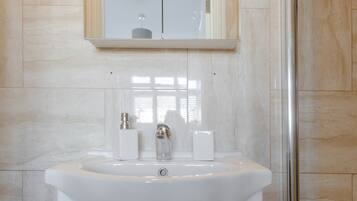 A bathroom with a white sink, mirror, and cabinets.