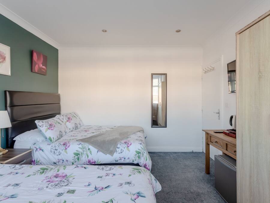 Un dormitorio con cama, mesita de noche, cómoda y espejo.