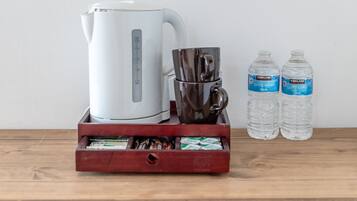 A white kettle, a coffee pot, and two water bottles on a wooden surface.