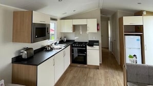 A compact kitchen with a microwave, toaster, and stove, a small dining area with a sofa, and a refrigerator.