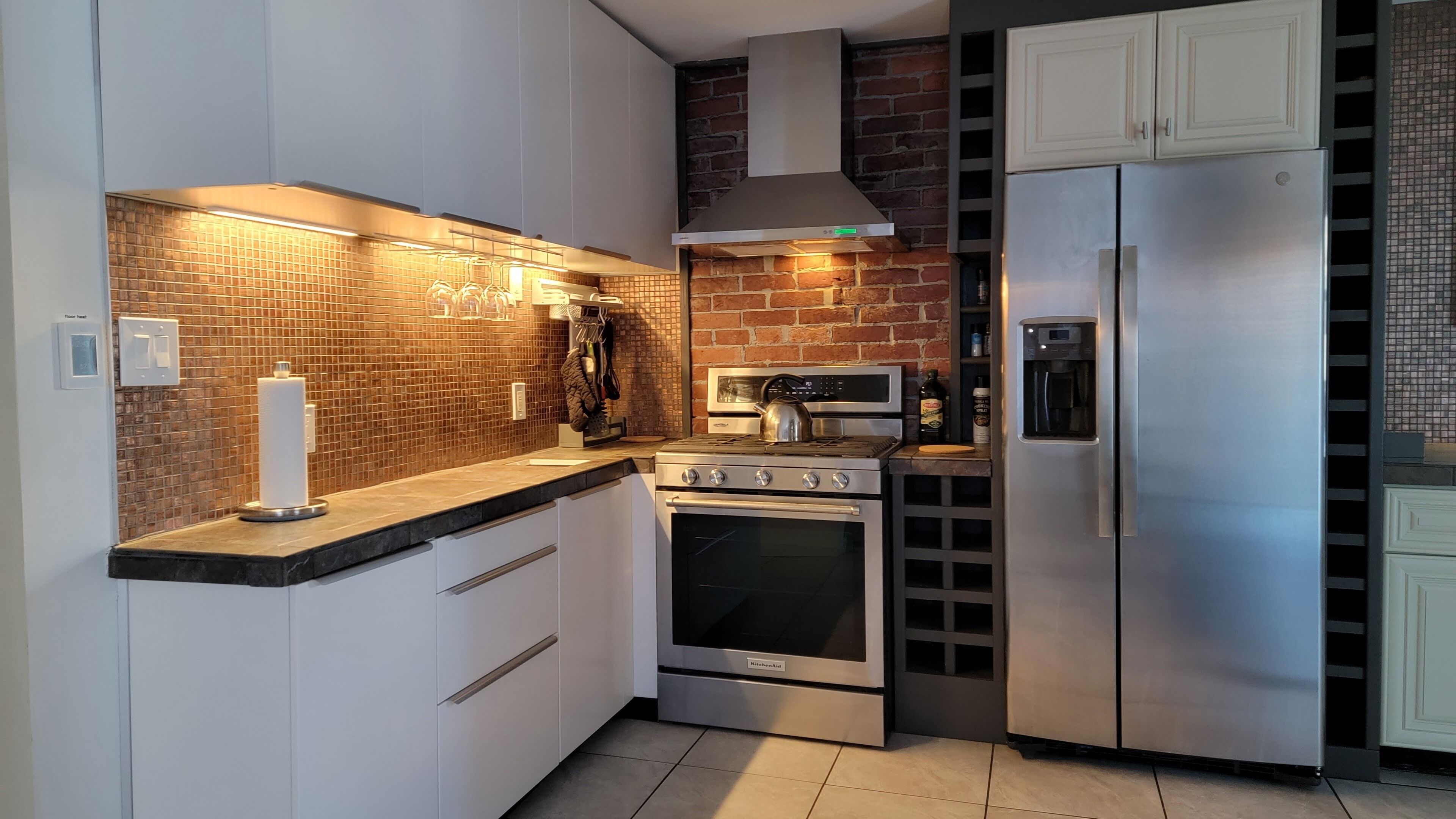 A modern kitchen with white cabinets, a stainless steel refrigerator, a built-in oven, and a microwave.