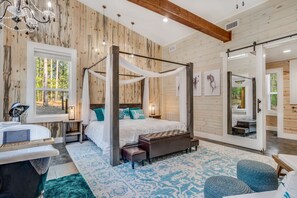 A four-poster canopy bed with a view of trees through a window, a bathtub, and a large mirror reflecting the room. - Breakfast at Tiffanys Cabin- Hot Tub/ Swing Bed/ Firepit/ 2-Person Soaker Tub (Broken Bow)