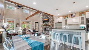 A spacious living area with a fireplace, a dining table, and a bar area with stools.