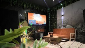 Un salon moderne avec un téléviseur à écran plat, des meubles en bois et une plante verte au premier plan.