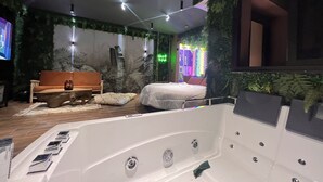 Une chambre moderne avec une grande baignoire blanche, un canapé et un lit.