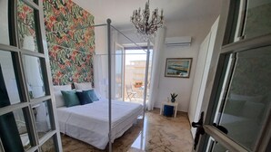 A bedroom with a bed, a chandelier, a painting, and a view of the outside. - Family sized trendy flat in the heart of Marsala with balconies and sea view (Marsala)