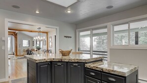 A modern kitchen with dark cabinetry, granite countertops, and a large island. - Quinn Peaks Retreat House with a hot tub! (Bozeman)