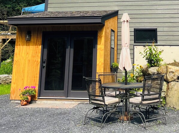 Relax in this inviting outdoor seating area with a round table and four comfortable chairs, shaded by an umbrella.