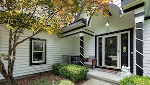 A house with a covered porch, a small garden, and a statue. - Peaceful Luxury Unique 3 BDR Home w/ Cinema & More (Traverse City)