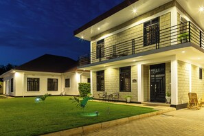A two-story modern house with a well-maintained lawn, outdoor seating, and a balcony. - Sarita Village - Serene Homestay Experience in Arusha's Outskirts. (Arusha)