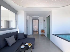 Una sala de estar moderna con un sofá, una mesa de centro y vistas a una piscina.