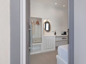 Un baño moderno con ducha a ras de suelo, tocador con espejo e inodoro.