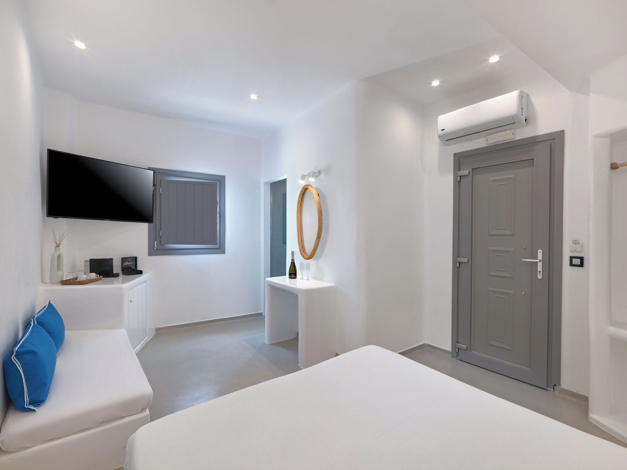 Un dormitorio moderno con cama, televisor, ventana, puerta y unidad de aire acondicionado.