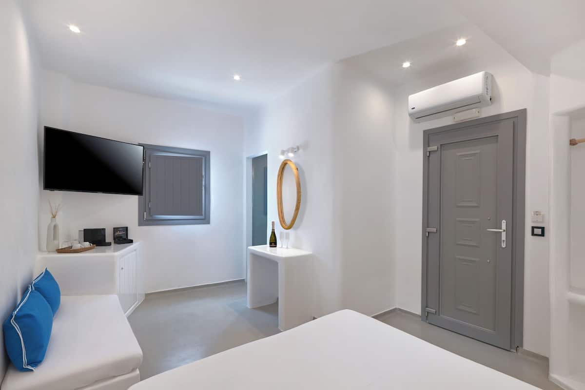 Un dormitorio moderno con cama, televisor, ventana, puerta y unidad de aire acondicionado.