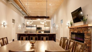 A modern kitchen with stainless steel appliances, a wooden dining table with chairs, and a stone fireplace. - Tall Oaks Resort (Willoughby)
