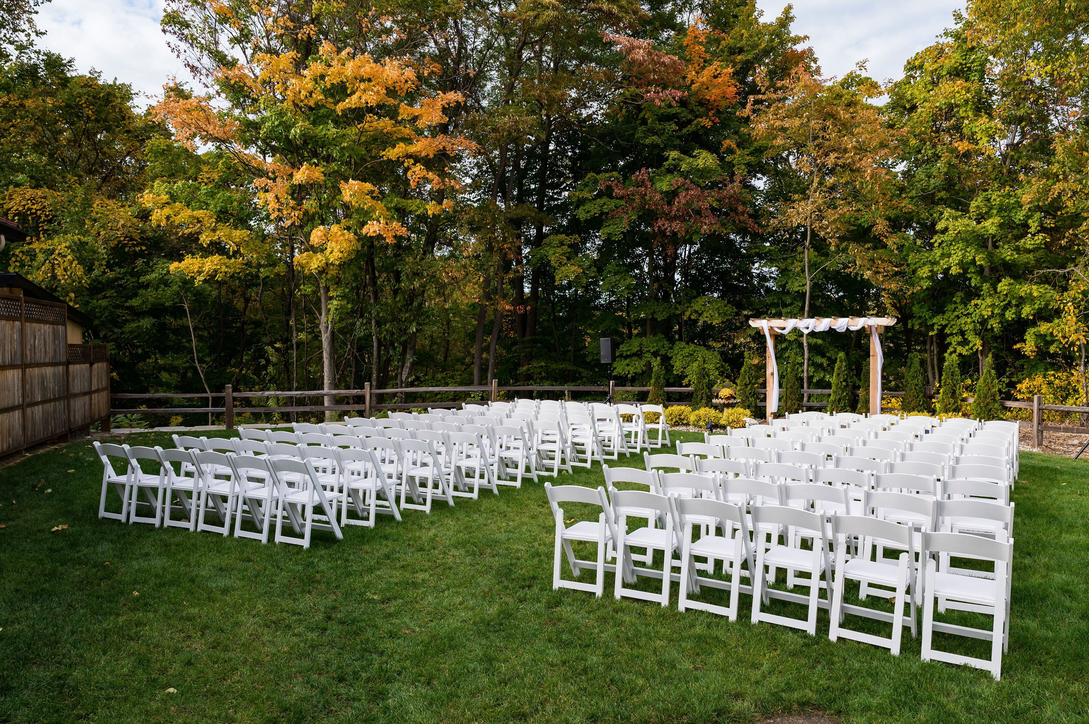 A grassy outdoor area with rows of white chairs arranged for an event.