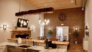 A modern kitchen with a stone fireplace, wooden ceiling, and pendant lighting. - Tall Oaks Resort (Willoughby)
