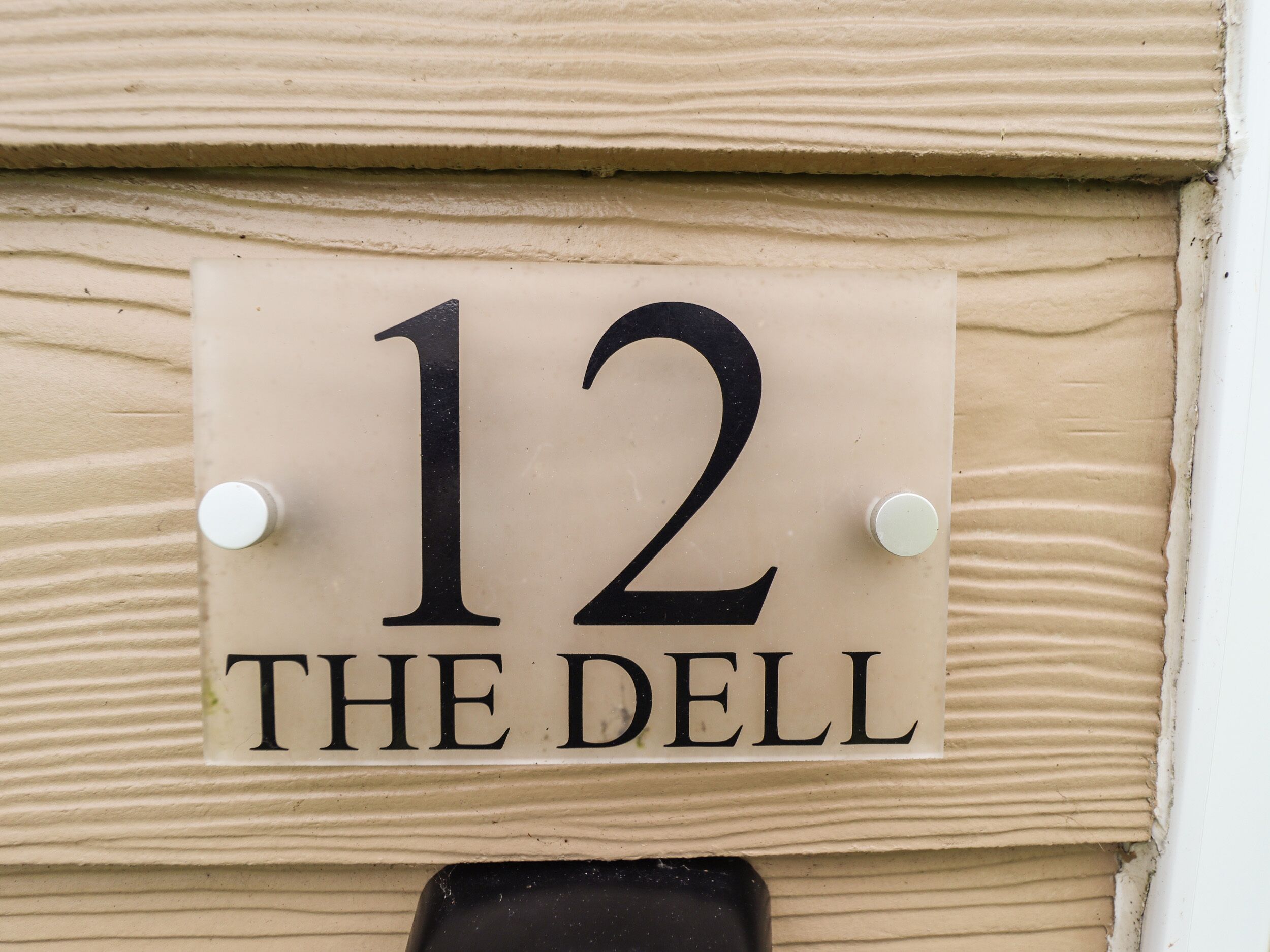 Un cartel con el número 12 y la inscripción 'THE DELL' sobre una pared color beige.