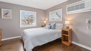 Un dormitorio con una cama, dos lámparas de noche, una mesita de noche y una ventana con persianas.