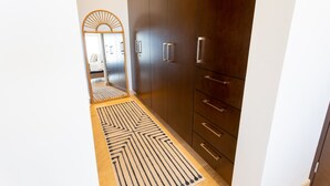 A hallway with a patterned rug, dark wooden wardrobe, and a mirror with a sunburst design. - Pedregal Penthouse Condo with Expansive Ocean Views (El, Pedregal)