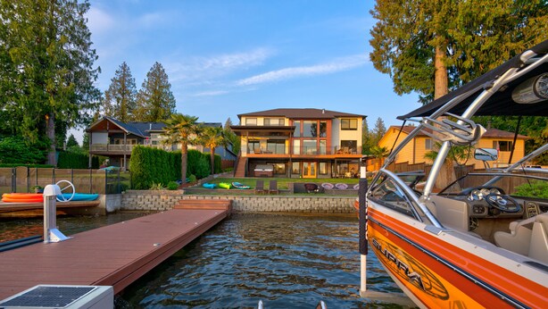 A modern house with a dock extending into a calm body of water.