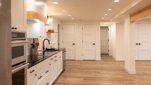 A modern kitchen with white cabinets, a black countertop, and wooden flooring. There are white doors leading to other rooms.