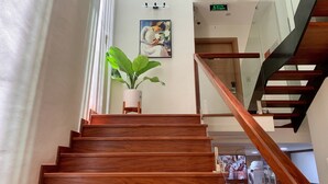 A wooden staircase with a potted plant at the top. - J'adore Apartment (Hanoi)