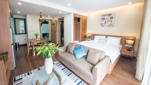 A modern hotel room with a large bed, a sofa, a dining area, and a bathroom visible through an open door. - J'adore Apartment (Hanoi)