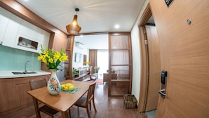 A modern kitchen with a dining area, wooden cabinets, a vase with flowers, and a sign indicating room number 502. - J'adore Apartment (Hanoi)