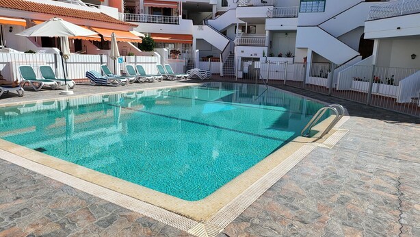 Ein Schwimmbecken mit Liegestühlen und einer gefliesten Terrasse.