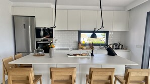 Une cuisine moderne dotée d’un îlot central, de meubles blancs et de chaises en bois.