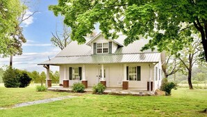 A single-story house with a front porch, a chimney, and a well-maintained lawn.