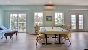 Un coin repas avec une table dressée pour quatre personnes, entourée de chaises, et un banc au premier plan.
