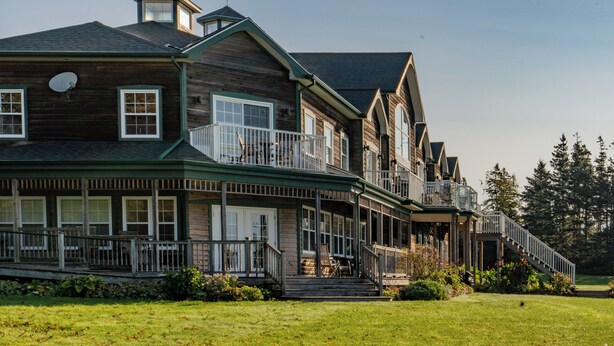 Une grande maison en bois à plusieurs étages, dotée de nombreux balcons et d’un porche couvert.